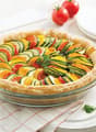 Colorful vegetable tart or quiche with sliced zucchini, tomatoes, and other vegetables arranged in a pie crust