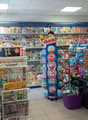 Candy store with magazines, shelves with candy and toys, candy dispenser, counter with candies, magazines rack