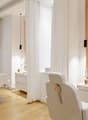 modern spa room, white walls, two white chairs, wooden floor, white curtains, white cabinets, metal fixtures