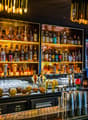 bar counter with multiple shelves filled with alcohol, various glasses and bottles, a hot air balloon, fruits, lamps, and decorations