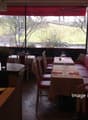A restaurant with tables and chairs, a counter, a monitor, a lamp, and a red awning.