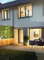 2 story house, gray walls, wooden doors, large windows, dining table with chairs in terrace, potted plants
