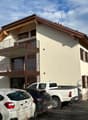two-story house, cream colored walls, brown roof, balconies, parked cars