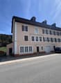 3 story building, beige and brown exterior, multiple windows, 2 garages, 2 cars parked in front
