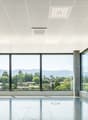 Large open office space with floor-to-ceiling windows offering a panoramic view of the surrounding mountains and greenery. The space features a clean, modern design with a tiled floor, recessed lighting, and a minimalist aesthetic.