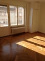 empty room, wooden parquet flooring, large windows, wooden door, white radiator, wooden built-in closets, power outlet