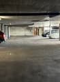 Indoor parking garage with concrete floor, concrete ceiling, and several parked cars