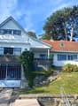 Two story house, white exterior, red tile roof, metal garage doors, large balcony, steps leading up to the front entrance