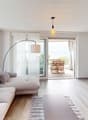 open plan living area, large windows, balcony, modern furniture, couch, TV, center table, arc lamp