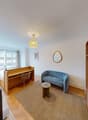 study room with desk and chair, couch, round table, carpet, lamp, television, potted plant, mirror, picture frame, window with curtains