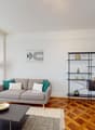 open living room, grey couch, table, wooden floor, lamps, shelves