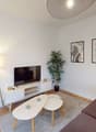 Living room: white walls, brown sofa, white coffee tables, television, lamp, plant