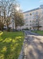 Building exterior with multiple floors, glass windows, front garden, driveway, and landscaping