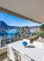 glass railing, large balcony, lake and mountain view, outdoor table and chairs, potted plants