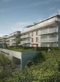 Multistory apartment building, with multiple balconies and windows, greenery, driveway and parking