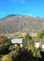 Aerial view of a town with mountains in the background, several buildings, trees, and solar panels