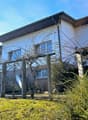 Modern white house on slope, with 2 windows and metal trellis in front