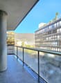 Balcony with glass railing, tiled floor, pillar, view of a building and mountain