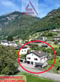 House in mountain village, white exterior, large windows, driveway, surrounding trees and plants