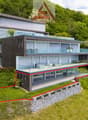 Modern house with terrace and glass windows, built on a sloped area