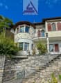 Two-story house, stone wall, balcony, arch windows, statue on top of the wall