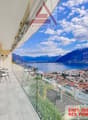 Balcony with glass railing, table and chairs, glass doors, scenic mountain and lake view