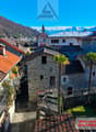 Stone buildings, red roofs, balconies, mountains in the background