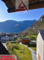 Aerial view of a village with a building, surrounded by mountains and a green field