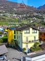 Large multi-story building, yellow paint, balcony, mountain view