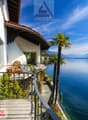 House with balcony, overlooking the lake, mountains in the background, palm trees