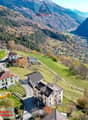 Mountain village with several houses, green fields, and a valley in the background