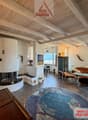 wooden ceiling, fireplace, large windows, couch, armchairs, rug, side table, artwork