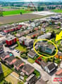 Aerial view of a residential area with various buildings, including a highlighted building with a yellow circle and arrow pointing to it.