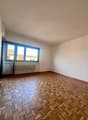 Empty room with wooden parquet floor, white walls, large window, white radiator, sliding glass door