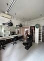 A salon space with chairs, a mirror, lamps, and a sink