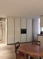 white cabinets, wooden table, chairs, integrated oven, large artwork, modern lighting