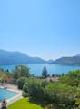 Pool with a lake view, greenery, a table with chairs