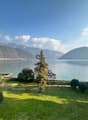 Green lawn, various trees and bushes, distant mountains, lake with a dock