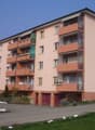 Apartment building with balconies, garages, and parking in front