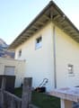 Single-family home, 2 stories, white exterior, small garden with grass, mountain backdrop
