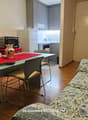 Table with 4 chairs, couch, microwave, refrigerator, flat screen TV, kitchen area