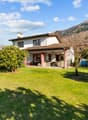 2 story house, white exterior, brown roof, large lawn, trees, mountains in the background