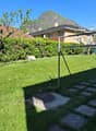 Green lawn, hedges, trees, playground equipment, mountains in the background