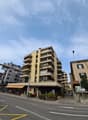 Multi-story building with balconies, storefronts, and a parking sign