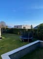 A garden with a trampoline, hedges, and a view of the mountains