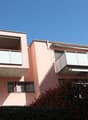 2 storey apartment building with pink exterior, two balconies