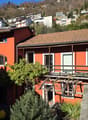 Terraced house, red brick walls, wooden balcony, windows with white frames, solar panels on the roof