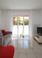 modern living room, gray sofa, red armchair, white coffee table, TV, white curtains, balcony, view of trees