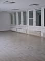 large room with white walls, wooden floors, windows, heating radiators, ceiling lights