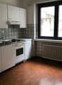 modern kitchen, white cabinets, tile flooring, gas stove, oven, sink, large window, radiator